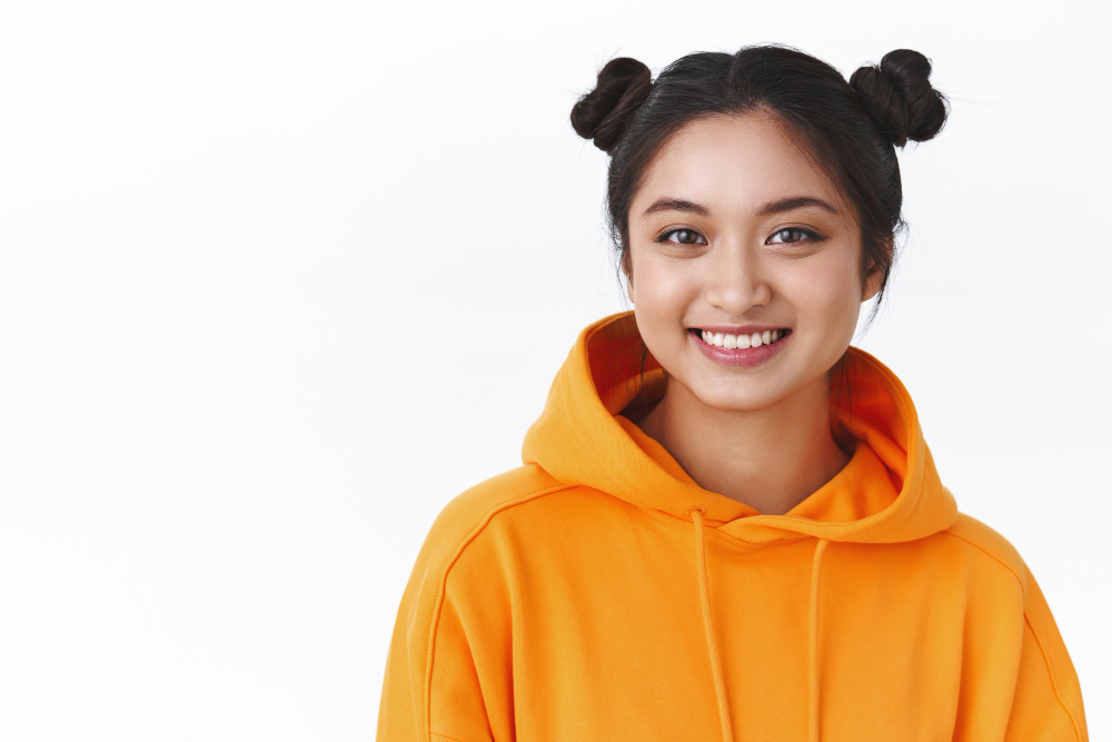 close-up-portrait-friendly-happy-kawaii-asian-girl-orange-hoodie-with-two-cute-hairbuns-smiling-happy-show-positive-joyful-emotions-standing-white-wall-concept-beauty